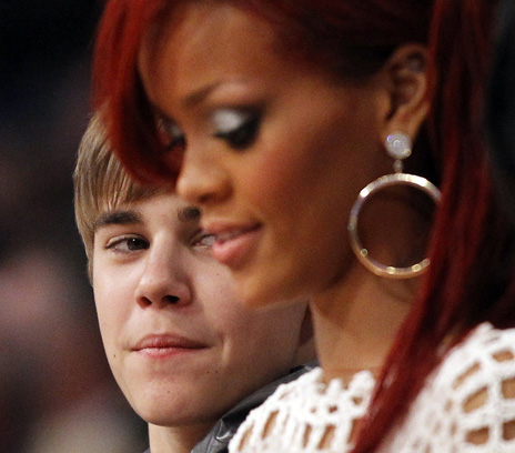 Justin Bieber looks over at Rihanna as they sit courtside during the NBA All-Star basketball game in Los Angeles